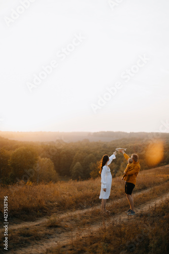 young family walks with a baby in the forest. family walk in the park. father plays with a child's toy outdoors. family evening walk at sunset. copy space from above. copy space left
