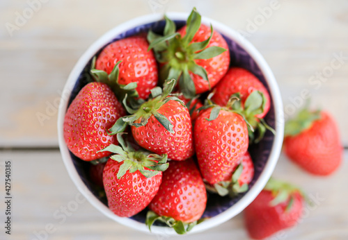 Fresh strawberries in a bowl on a wooden background. Healthy food. Top view.