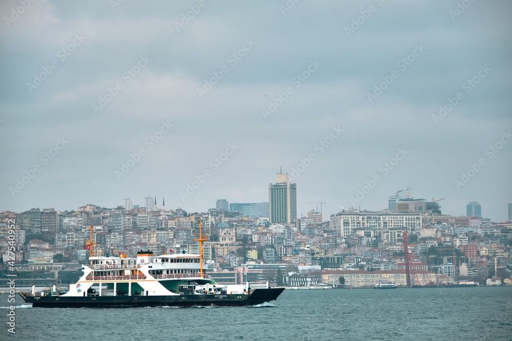 04.03.2021. istanbul turkey. Pedestrian ferry sailing on istanbul bosphorus during cloudy, rainy and overcast day with golden horn istanbul and city and buildings background.