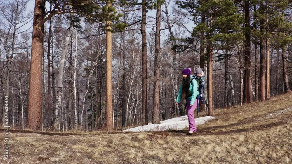 A young woman carries her young son in a backpack while traveling in the mountains. A young woman carries her young son in a backpack while traveling in the mountains.