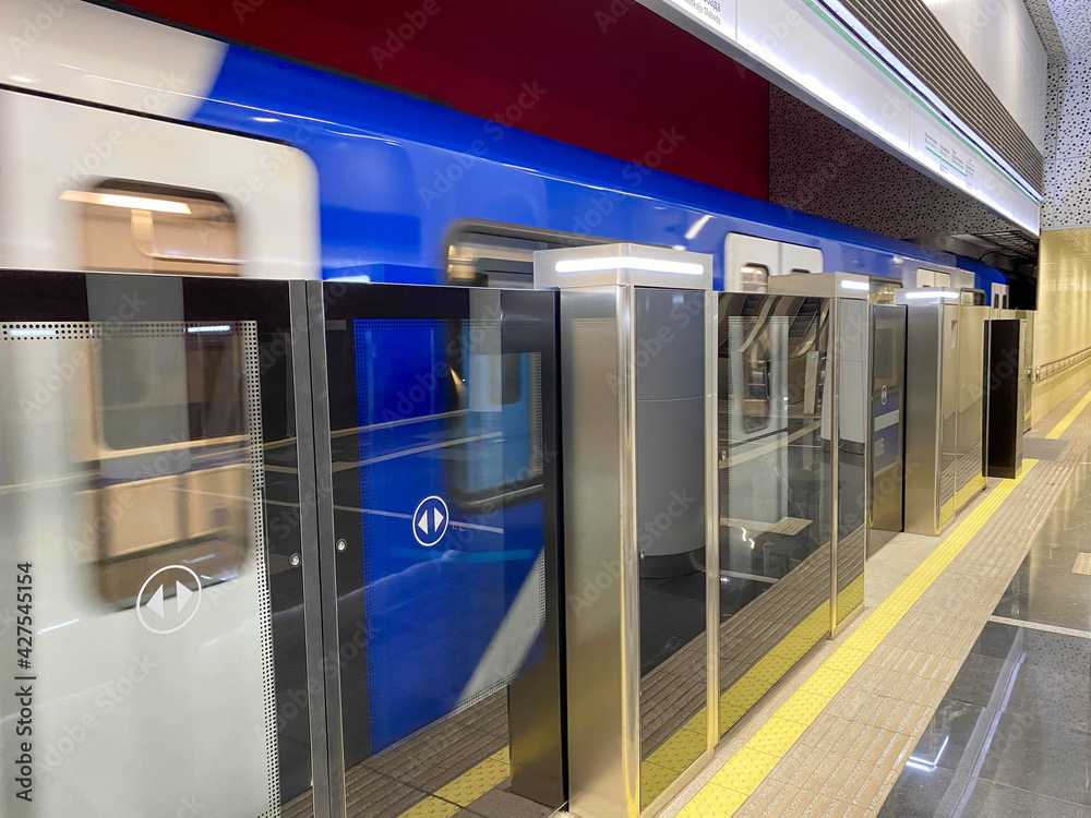 A blue train carriage with open and closed sliding mechanical door and man at a train metro station platform
