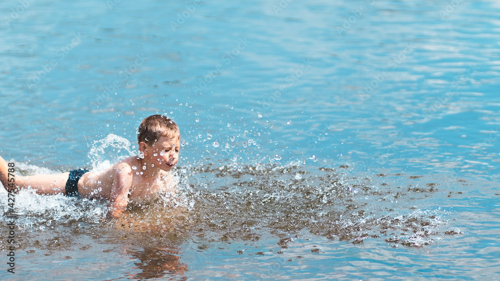 A little boy is learning to swim. A splash of water in the background.