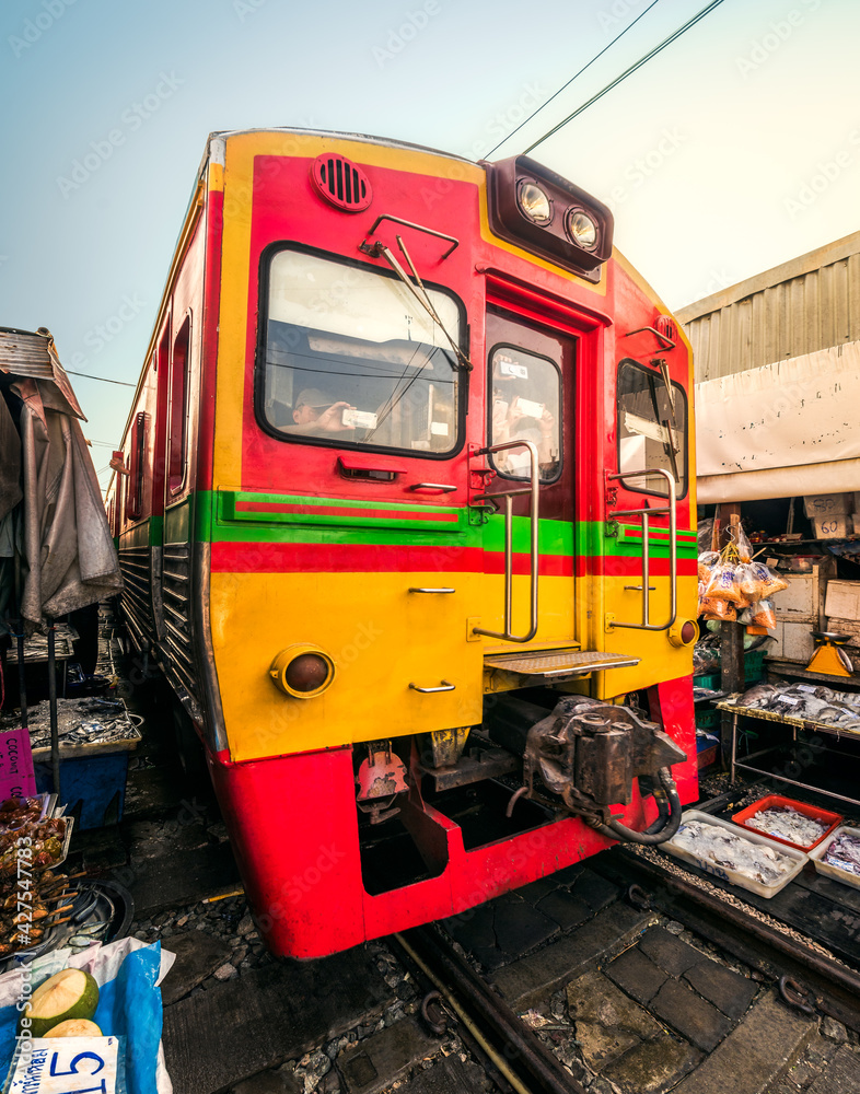 A Train on Umbrella Fresh Market on the Railroad Track, Mae Klong Train Station, Bangkok, Thailand on a Sunny Day