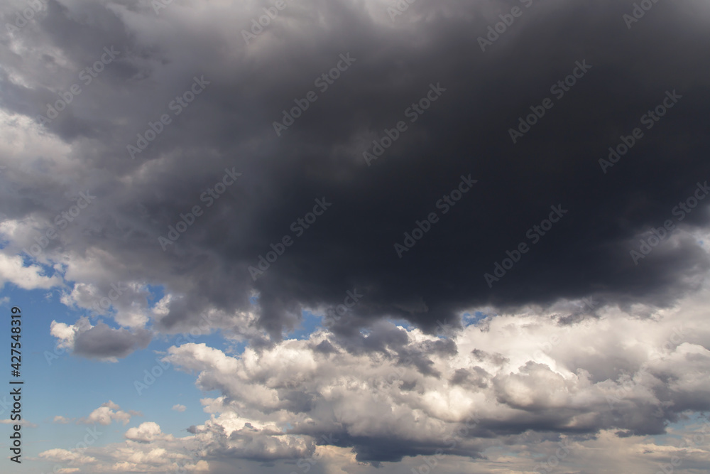 Thunderstorm clouds texture. Storm sky with dark rainy cumulus clouds against blue sky background Thunderstorm clouds texture. Storm sky with dark rainy cumulus clouds against blue sky background