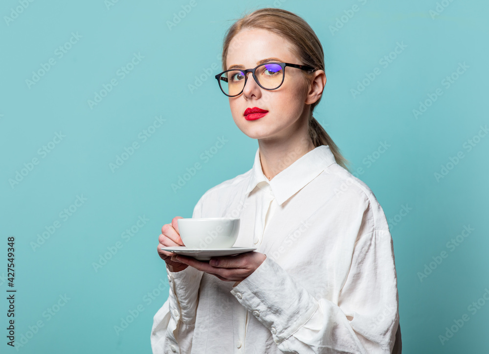 Portrait of beautiful blonde in white shirt with cup of coffee on blue background Portrait of beautiful blonde in white shirt with cup of coffee on blue background