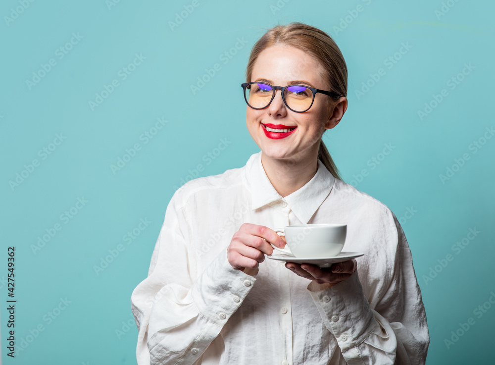 Portrait of beautiful blonde in white shirt with cup of coffee on blue background Portrait of beautiful blonde in white shirt with cup of coffee on blue background