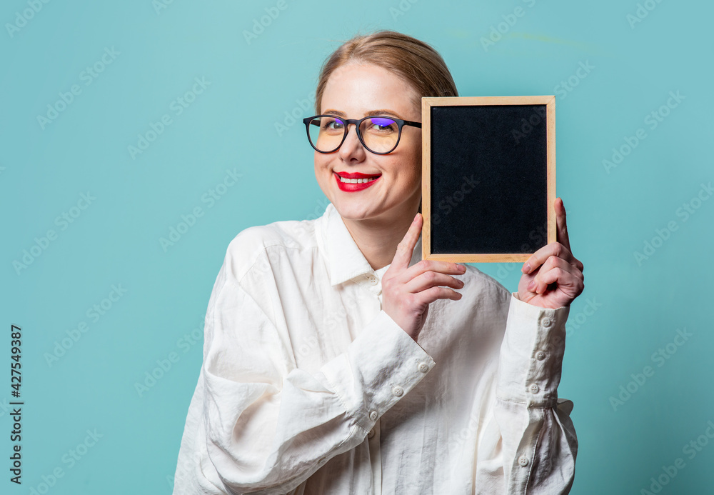 Portrait of beautiful blonde in white shirt with blackboard on blue background Portrait of beautiful blonde in white shirt with blackboard on blue background