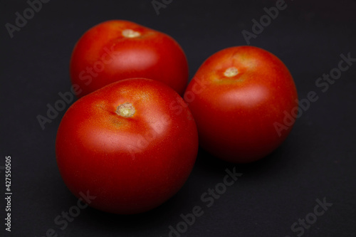 Zbliżenie na trzy czerwone dojrzałe pomidory na czarnym tle