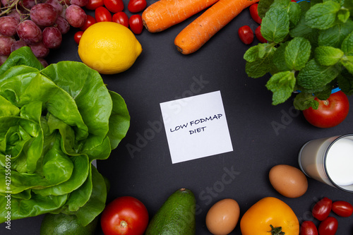 Biała karteczka na czarnym tle z napisem low FODMAP, otoczona warzywami i owocami z miejscem na tekst o diecie, zdrowym odżywianiu, nawykach żywieniowych. Flat lay
