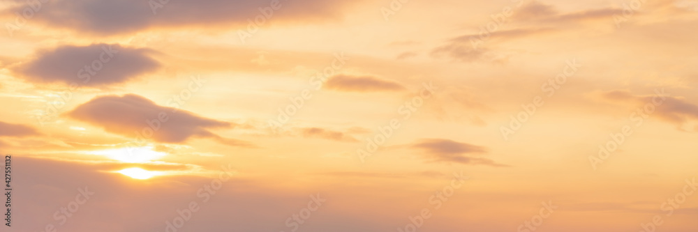 Beautiful sunset sky background with clouds and sun. Bright sunshine. Picturesque cloudscape. Wide panoramic background for design.