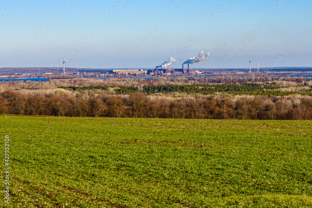 Fototapeta premium View on smoke pipes of the factory and agricultural field