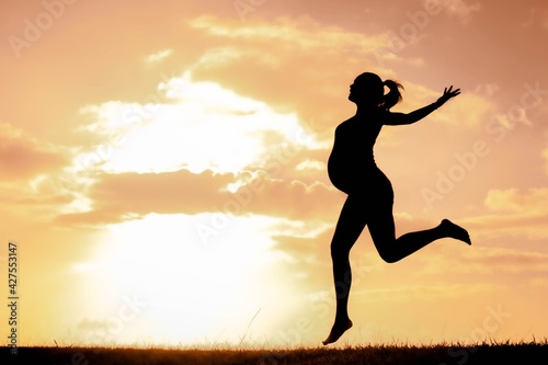 A happy active pregnant woman having fun and exercising outdoor in nature. Maternity and wellbeing.