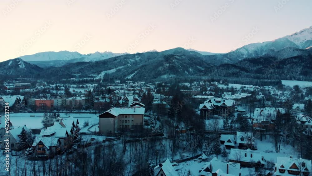 Picturesque view of the snow-capped mountains with clear sky. Aerial footage of snow-covered towns and streets during the winter season against the forest in the city of Zakopane, Poland. High Quality Picturesque view of the snow-capped mountains with clear sky. Aerial footage of snow-covered towns and streets during the winter season against the forest in the city of Zakopane, Poland. High Quality