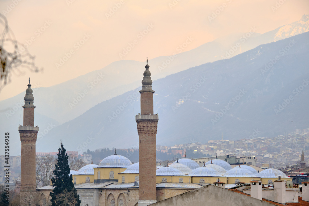 Bursa, Turkey 29.03.2021. Bursa during overcast and rainy day. Photo taken from tophane district through grand mosque (ulu camii) built by ottoman empire and with ulu mountain (uludag) background.