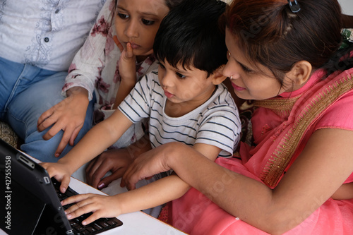 Happy Indian family watching something on their tablet while sitting on a couch photo