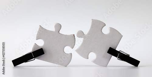 Tablou pe pânză Black wooden tongs and two white puzzles
