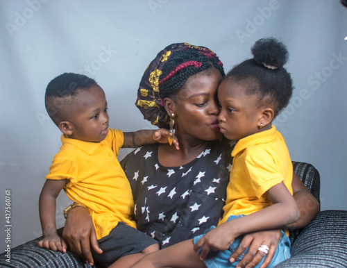 Happy family consisting of a mother and her boy and girl children sitting happily together and playing with a big smart phone or phone tab