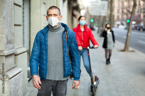 Adult man in medical mask walking to work along city street on spring day. New life reality during the coronavirus pandemic