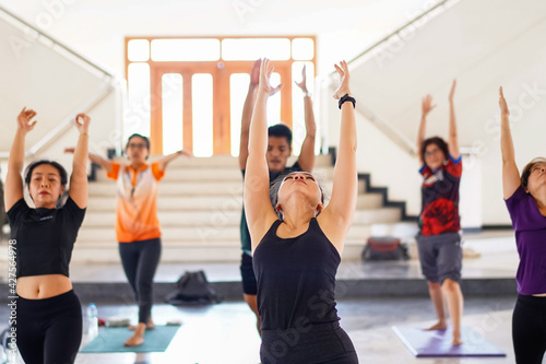 Group of people doing yoga training in yoga class in the indoor gymnasium to relax and get healthy health. Sport and recreation stock photo