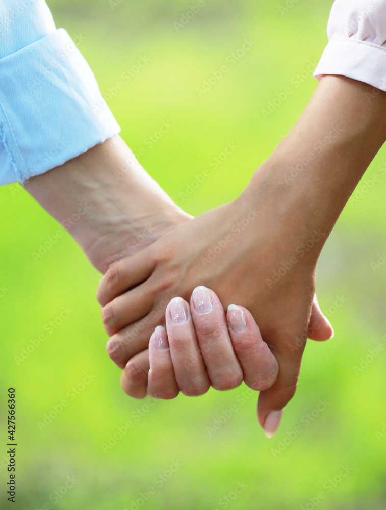 Elderly Mother holding a hand of her adult daughter in summer day outdoors Elderly Mother holding a hand of her adult daughter in summer day outdoors