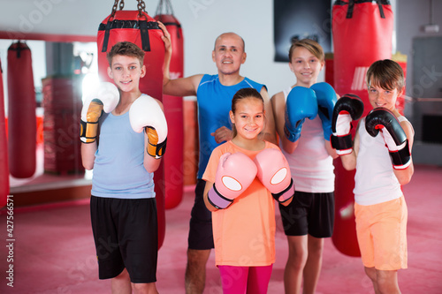 Group of teenagers posing in fighting stance at boxing gym with coach