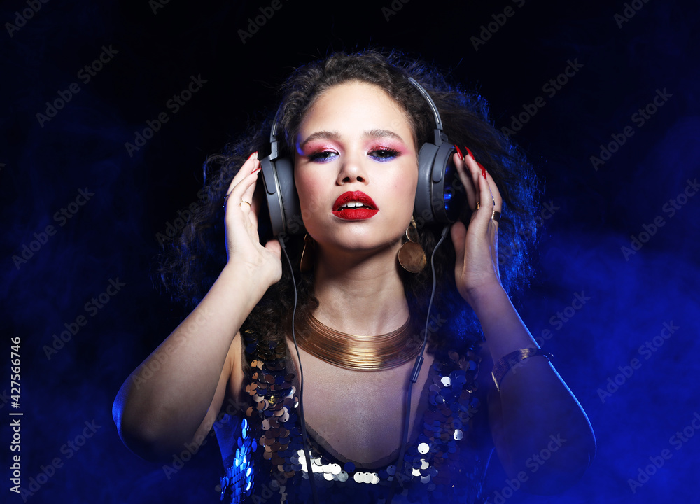 Beautiful young african woman with headphones, sings songs and listens to music