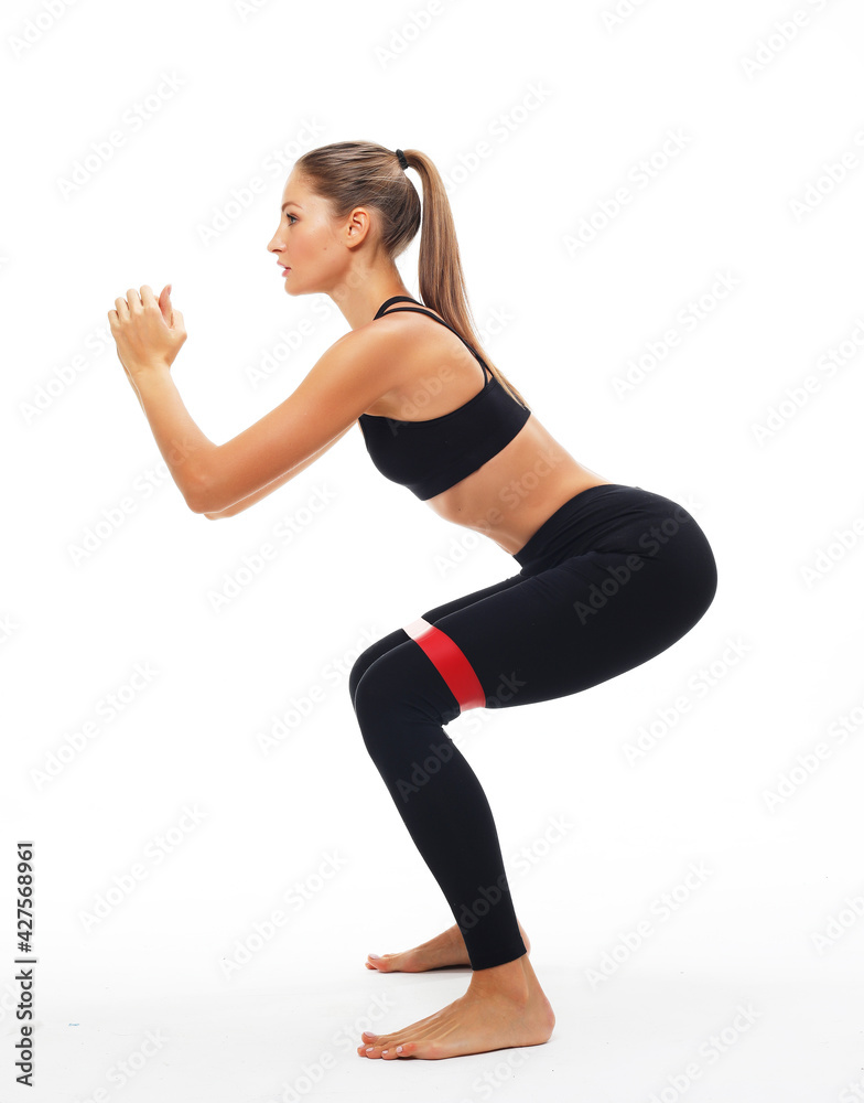 Strength and motivation. Sporty young woman squatting doing sit-ups with resistance band.
