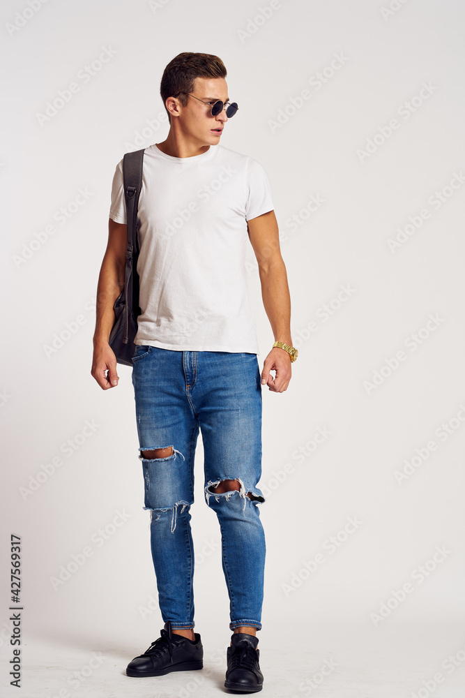 a man with a backpack on his back in jeans t-shirt full length sneakers and glasses on his face a man with a backpack on his back in jeans t-shirt full length sneakers and glasses on his face
