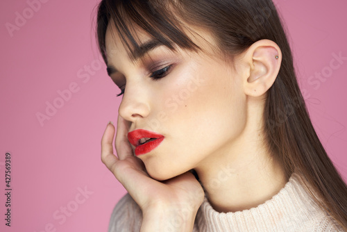 Pretty brunette in a white sweater red lips attractive look pink background