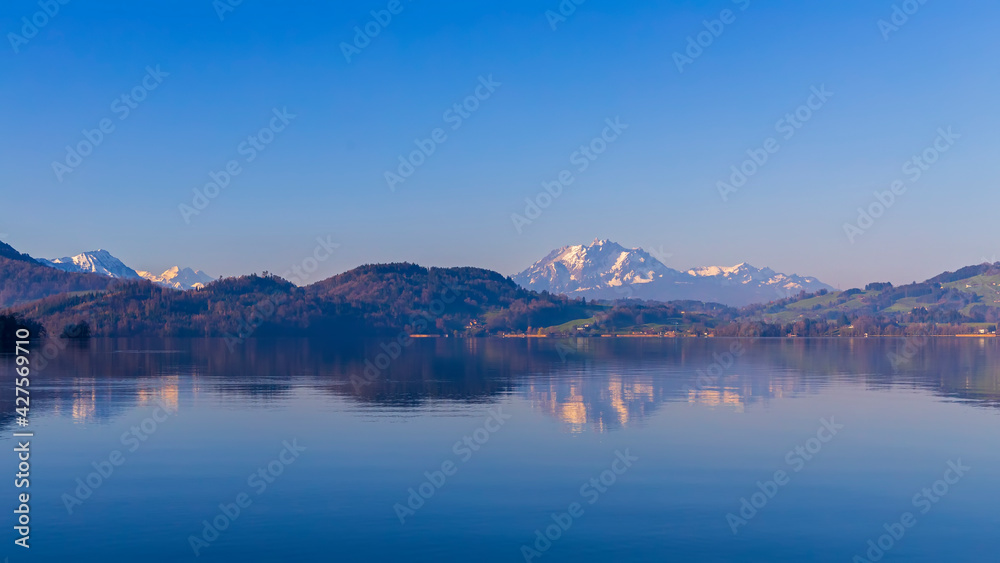 Beautiful lake view and snow cap mountain in morning sunrise with reflection.Panorama landscape of lake in Switzerland with Pilatus on background scene. Blue winter sky.