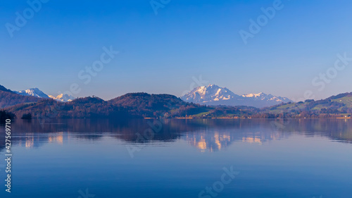 Beautiful lake view and snow cap mountain in morning sunrise with reflection.Panorama landscape of lake in Switzerland with Pilatus on background scene. Blue winter sky.