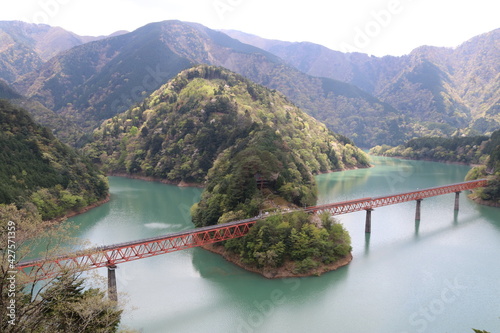 南アルプスの風景。湖上を走る鉄道。大井川鉄道奥大井湖上駅。大井川にある接岨湖（せっそこ）のかかる鉄橋、その途中に湖上駅がある。エメラルドグリーンの水に赤い鉄橋が映える。