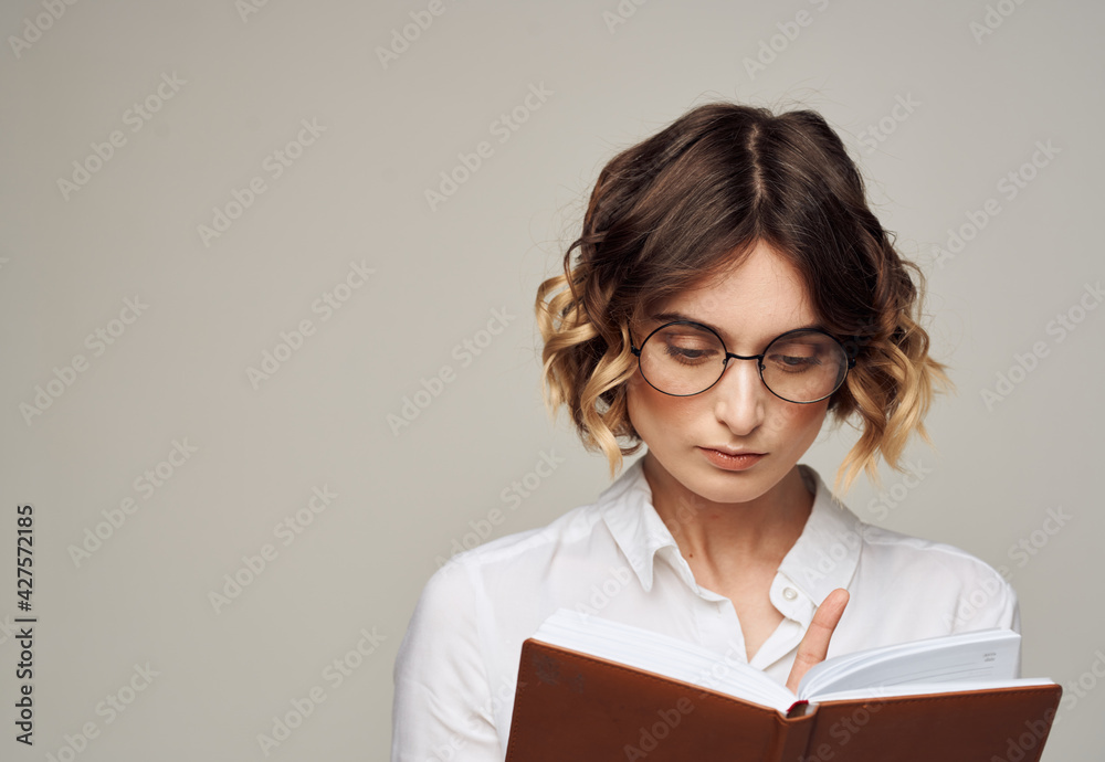 Business woman with open notebook in her hands and glasses on her face, white shirt Business woman with open notebook in her hands and glasses on her face, white shirt