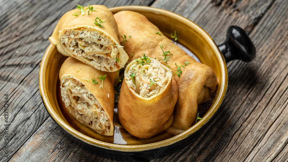 Stuffed pancakes or crepes rolls with chicken meat and cheese. Traditional Russian Shrovetide Maslenitsa festival meal. Food recipe background. Close up Stuffed pancakes or crepes rolls with chicken meat and cheese. Traditional Russian Shrovetide Maslenitsa festival meal. Food recipe background. Close up