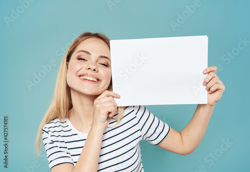 Beautiful blonde on a blue background with a white sheet of paper banner advertising positive gesture