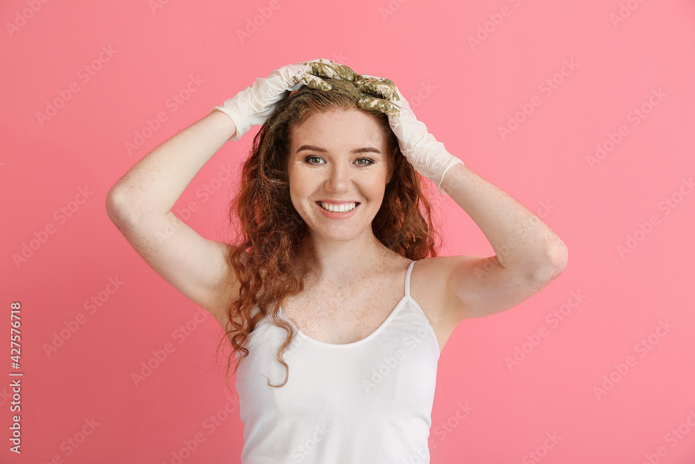 Young woman using henna hair dye on color background Young woman using henna hair dye on color background