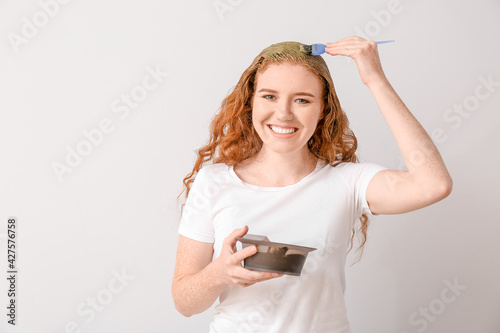 Canvastavla Young woman using henna hair dye on light background