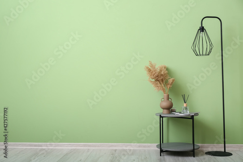 Table and floor lamp near color wall