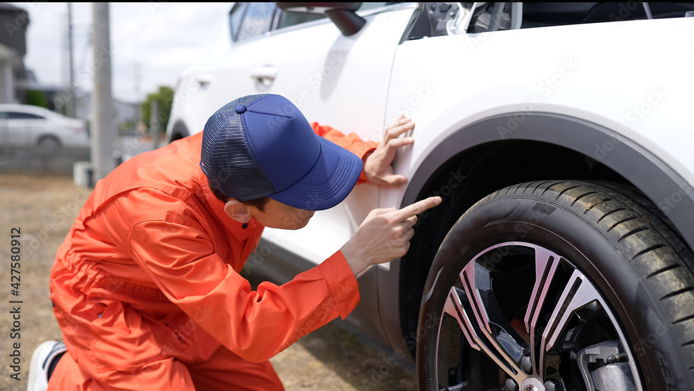 自動車のタイヤを点検する男性整備員 自動車のタイヤを点検する男性整備員