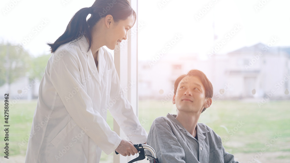 車椅子に乗った患者を励ます医師 車椅子に乗った患者を励ます医師