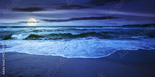 Obraz na płótnie sea tide on a cloudy sunrise. green waves crashing golden sandy beach in full moon light. storm weather approaching. summer holiday concept w salonie