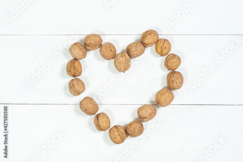 heart of whole walnuts on a light wooden background. Healthy food nuts.