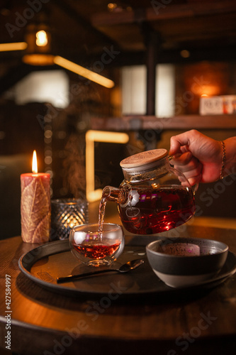 Tea brewing process, tea ceremony, freshly brewed red tea cup, warm soft light, dark background.