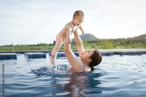 Happy family mother baby playing swimming pool on leisure summer vacation © Sutthiphong