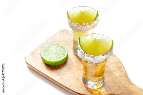 Tequila shots with lime slices on a wooden board on a white background