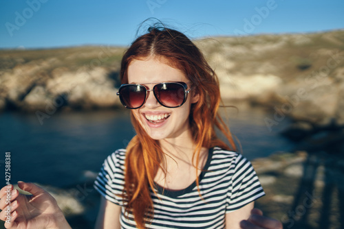 portrait of a happy traveler in a t-shirt and glasses and near the sea in the mountains