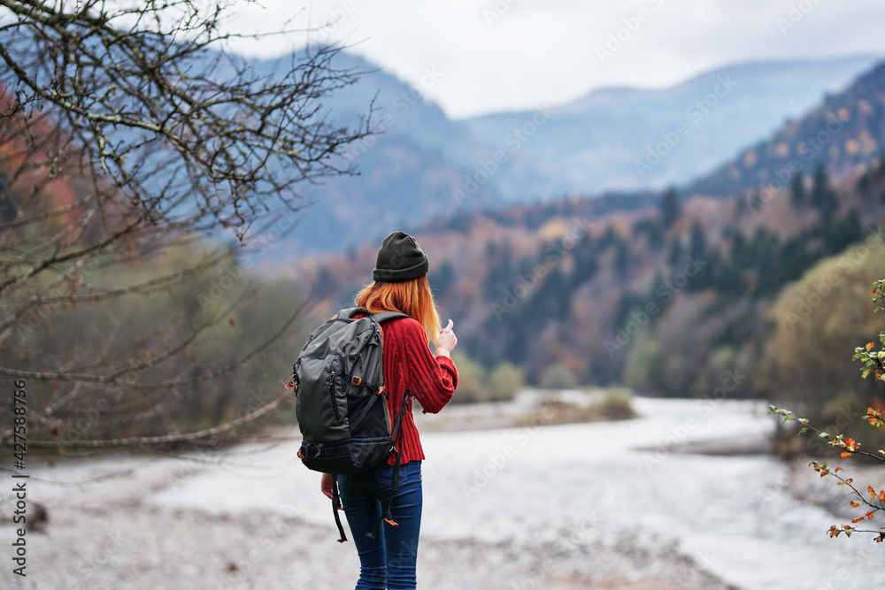 happy woman with backpack rest in the mountains near the river on nature autumn landscape fresh air