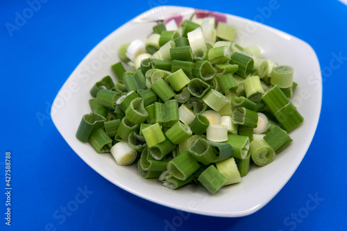 bowl with sliced spring onions on blue background