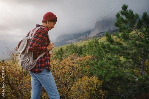 Happy young woman with backpack exploring misty mountains.