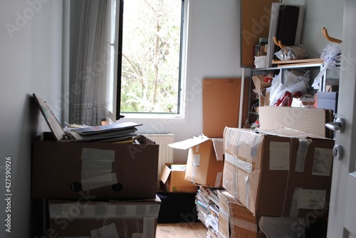 Moving packing concept. A room full of messy cardboard boxes with an opened window. 